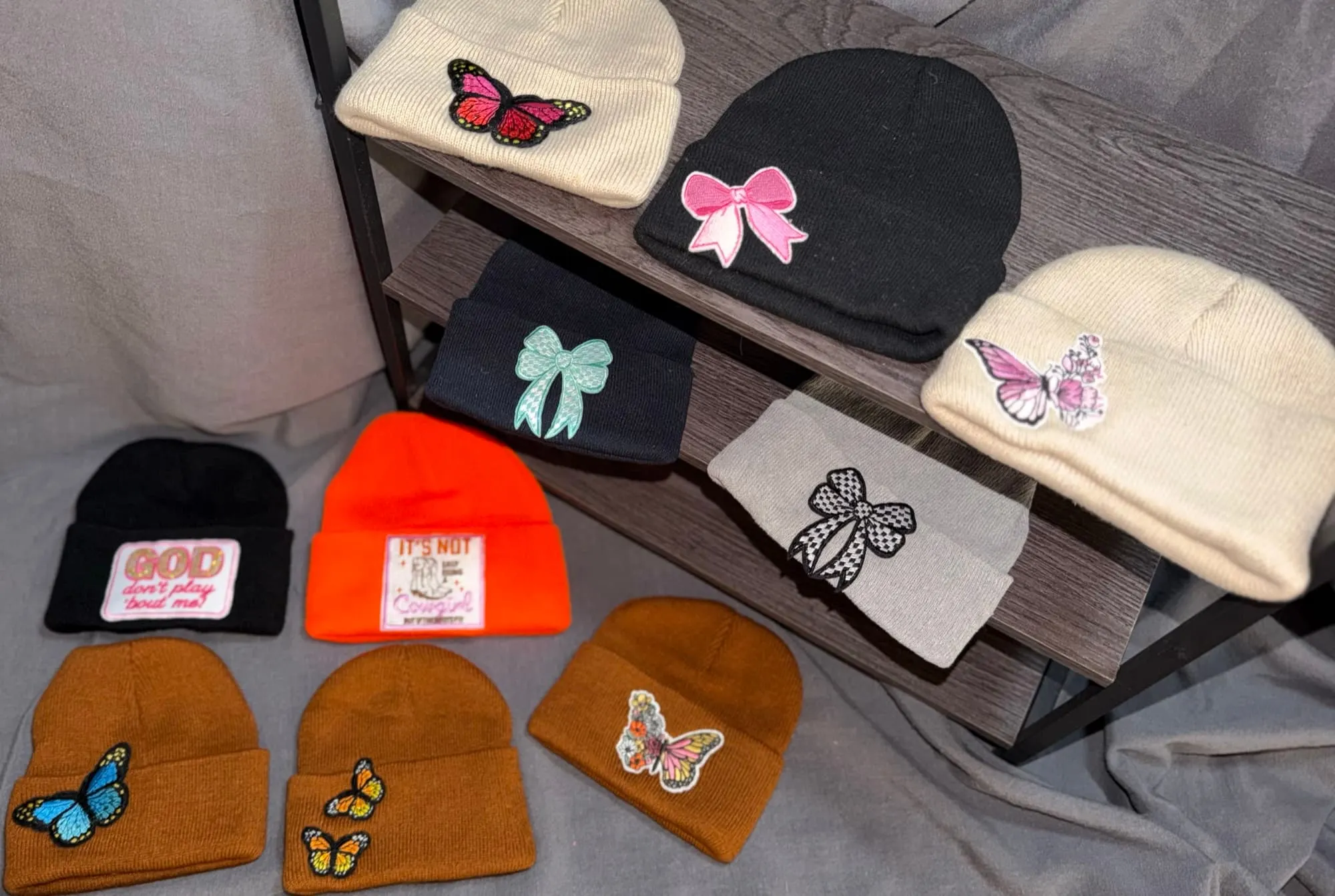 Ten patch beanies with butterflies and bows, plus God Don't Play 'Bout Me and It's Not Easy Being a Cowgirl