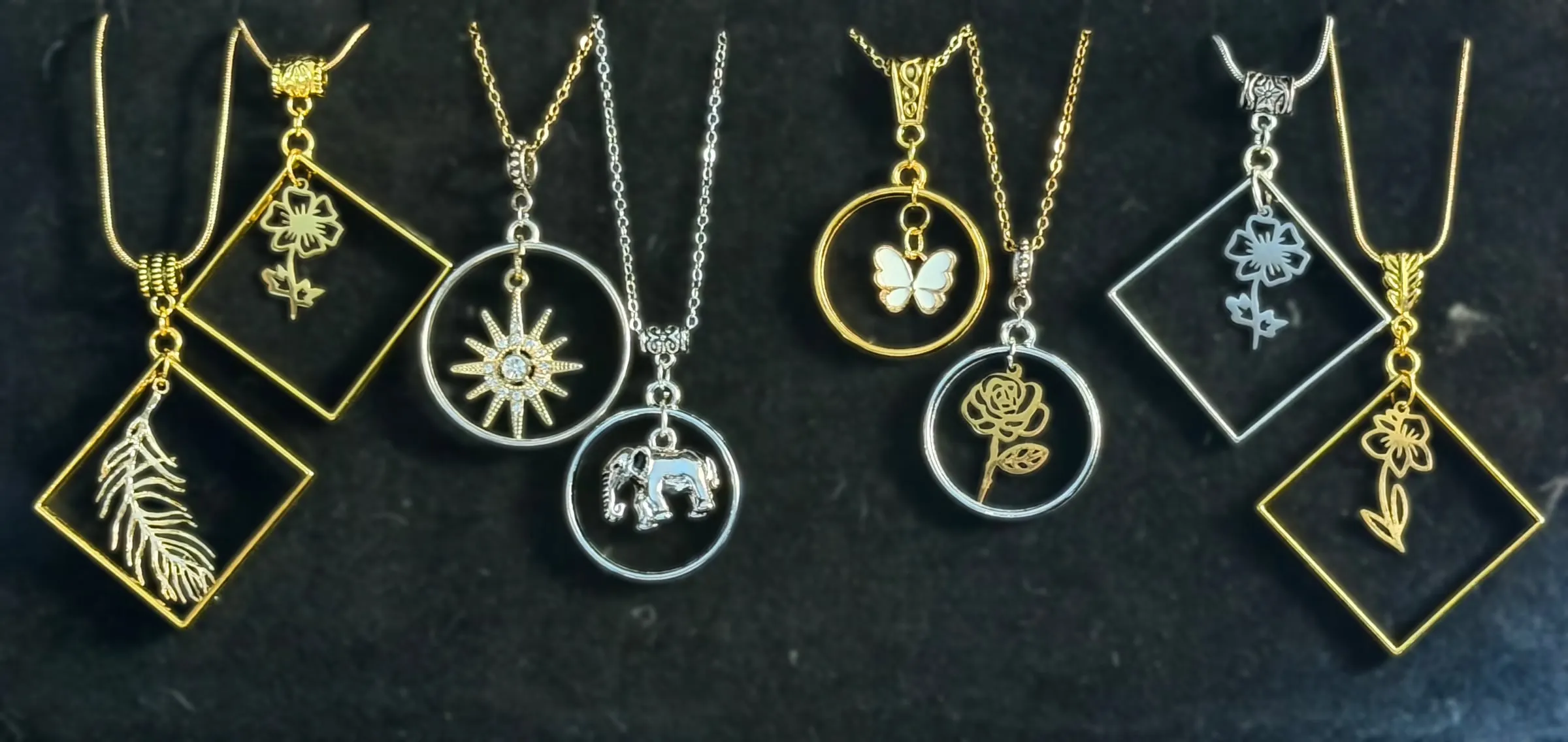 Eight framed pendants with feathers, flowers, a starburst, an elephant, a butterfly and a rose in gold and silver frames