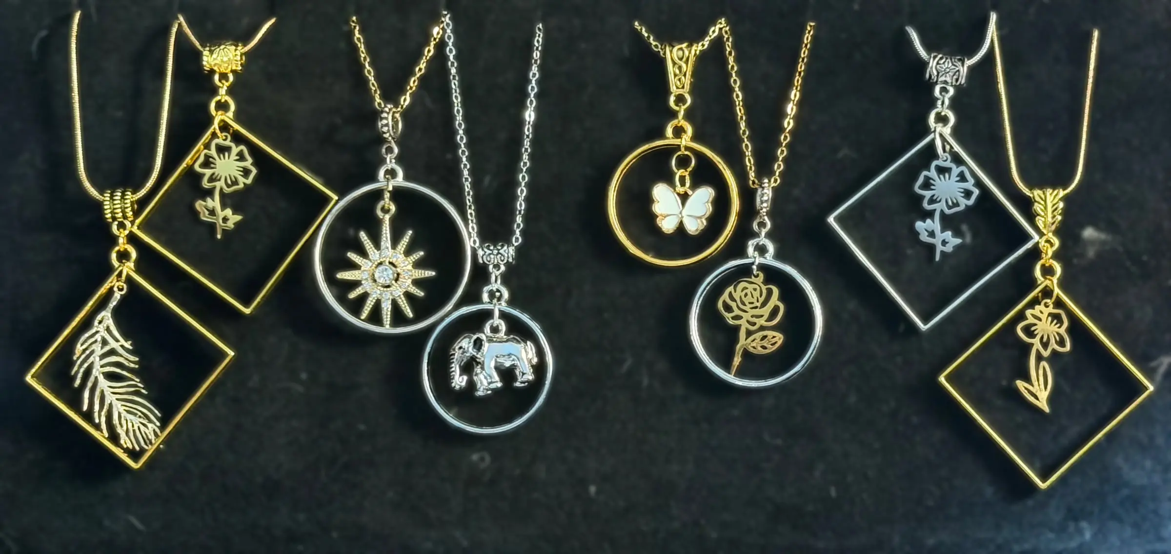 Eight framed pendants with feathers, flowers, a starburst, an elephant, a butterfly and a rose in gold and silver frames