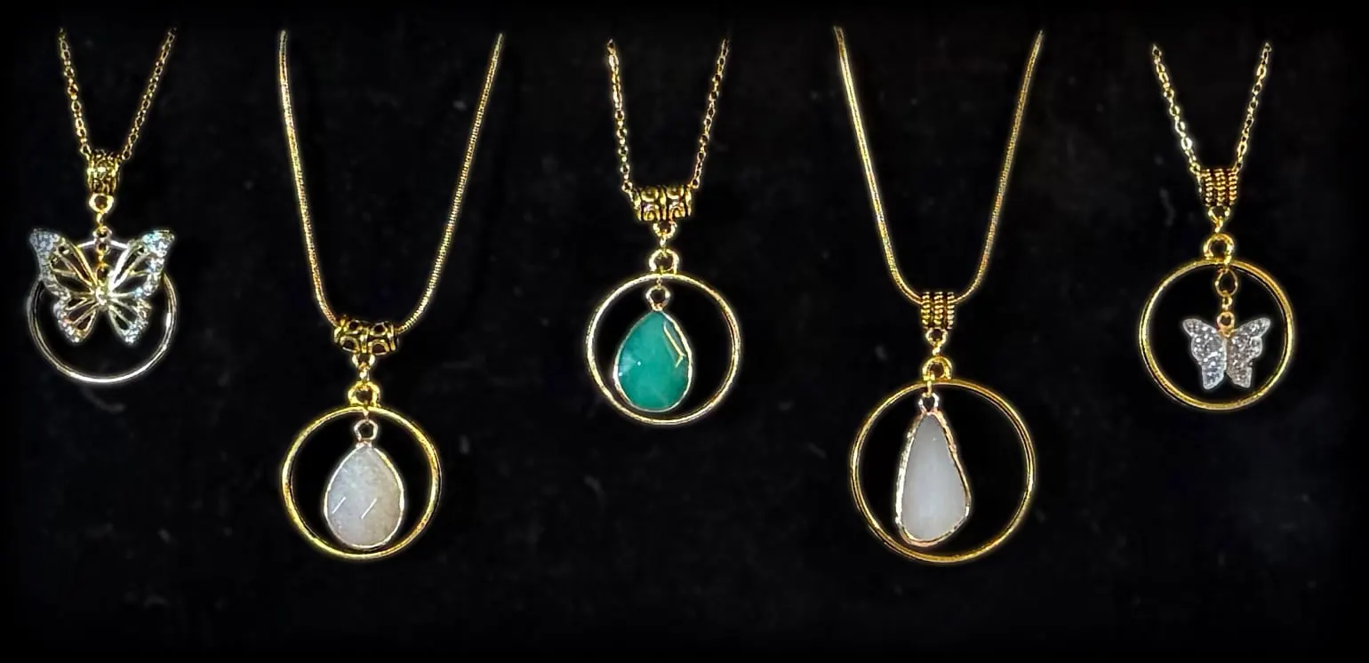 Five gold halo pendants: a butterfly, a rose quartz teardrop, a jade teardrop, a rose quartz drop and a glitter butterfly
