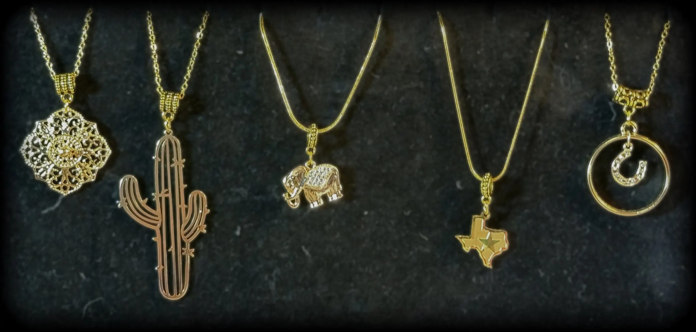 Five gold-tone charms: a filigree medallion, a rose gold saguaro, an elephant, a Texas charm and a horseshoe halo