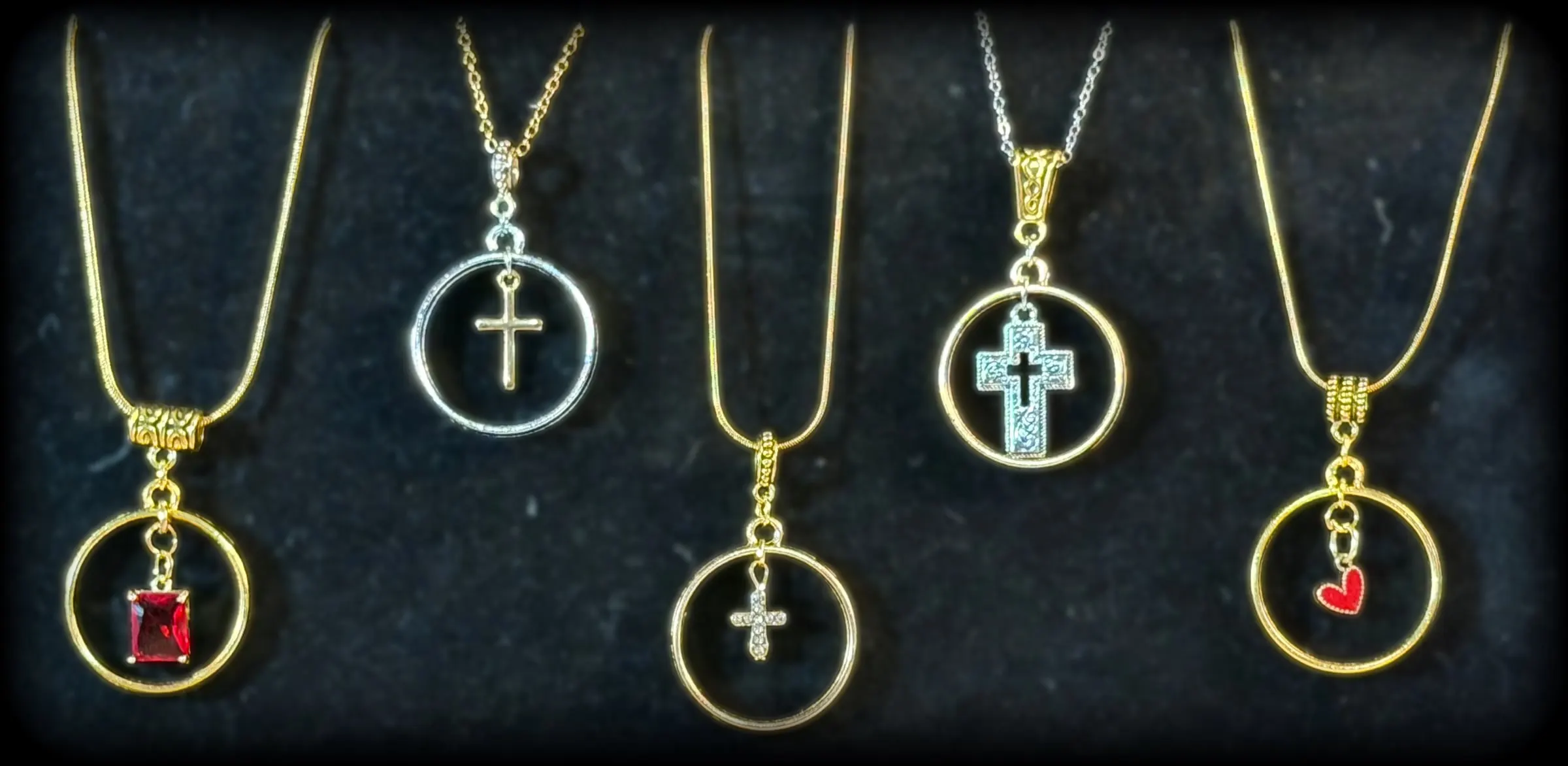 Five halo pendants: a red crystal in gold, a silver cross, a petite cross, an etched cross and a red heart