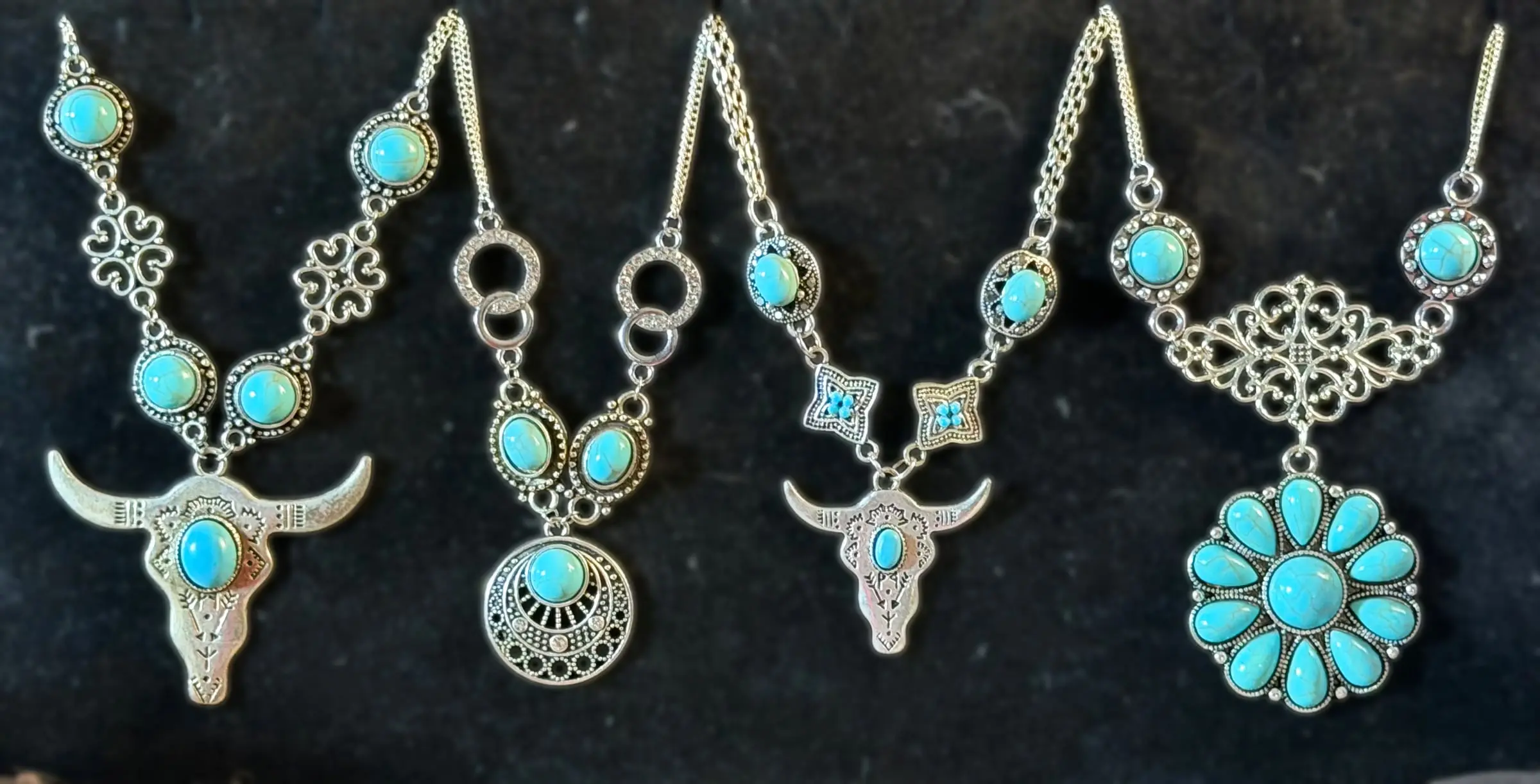 Four turquoise necklaces: a longhorn skull, a turquoise medallion on rings, a longhorn on star links and a turquoise blossom
