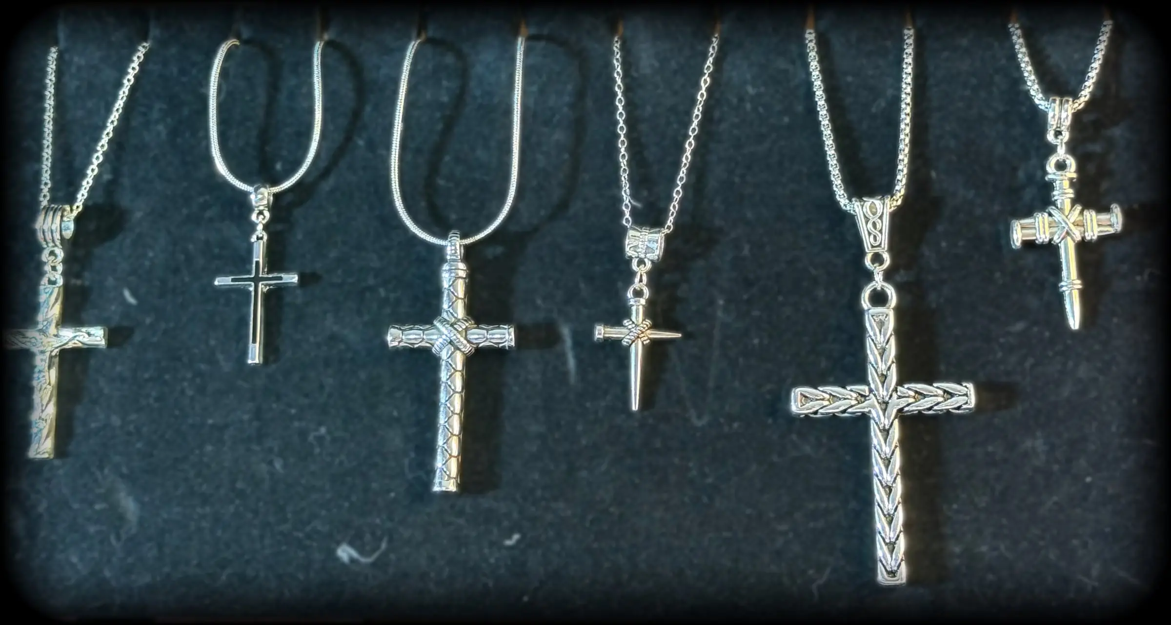 Six silver cross necklaces including nail-and-wire crosses and a braided cross