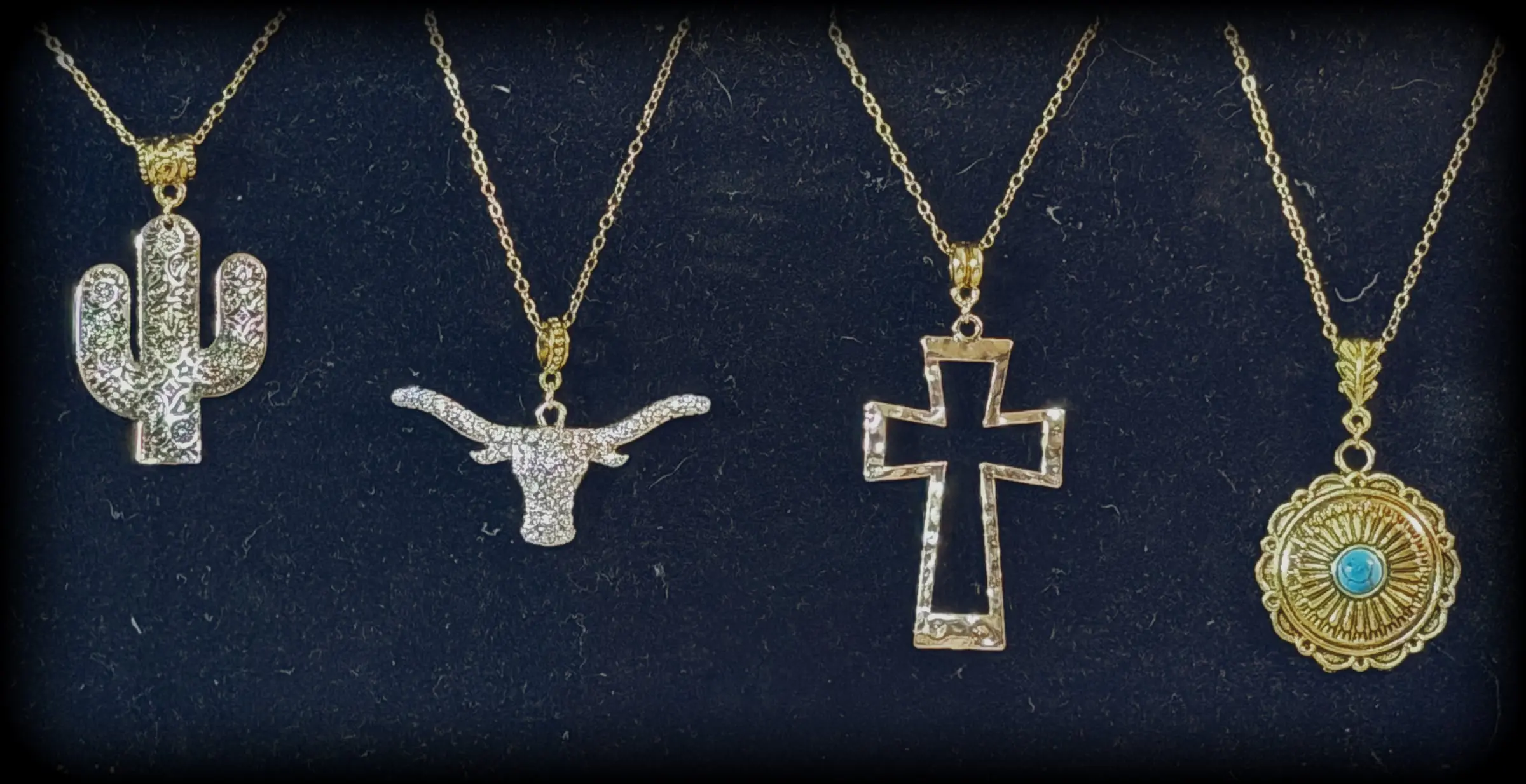 Four pendants: a rhinestone saguaro, a rhinestone longhorn, a hammered open cross and a gold turquoise concho