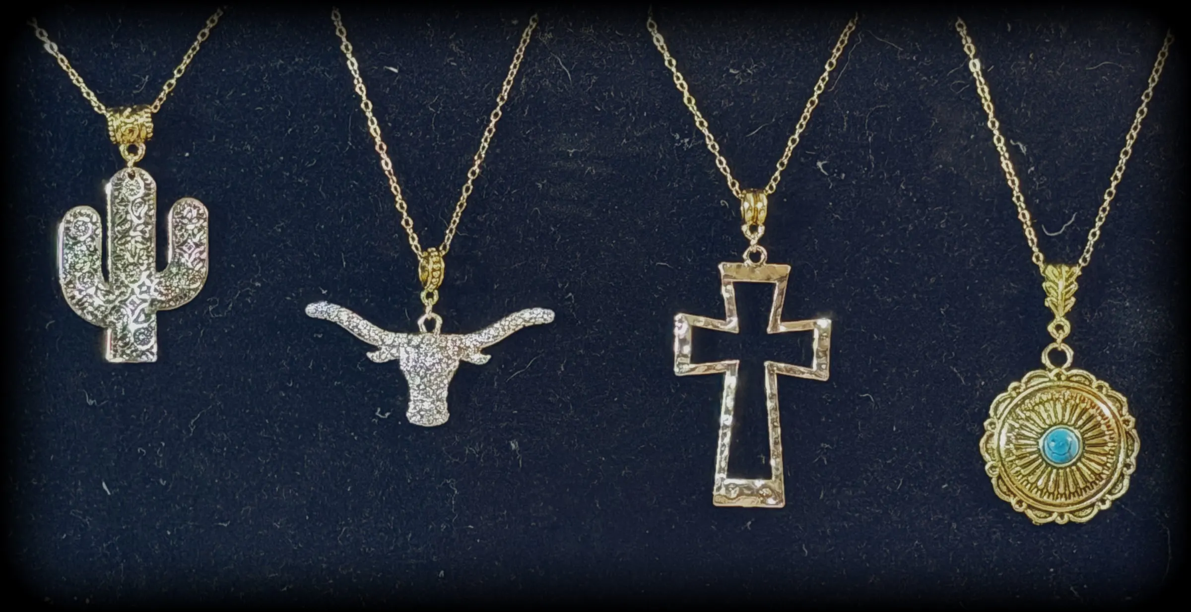 Four pendants: a rhinestone saguaro, a rhinestone longhorn, a hammered open cross and a gold turquoise concho