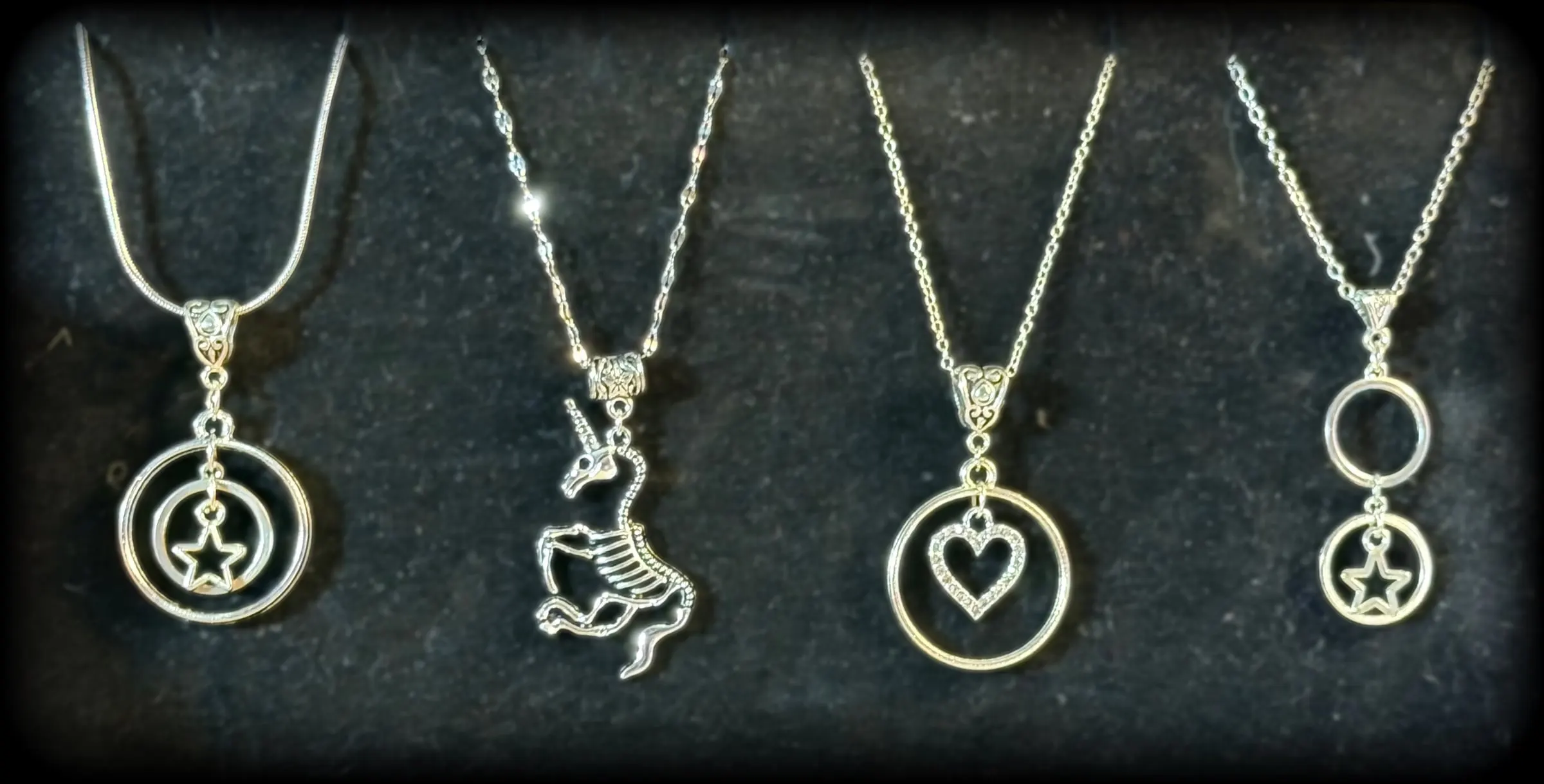 Four silver pendants: a star in double rings, a unicorn, a heart halo and a star with a double ring