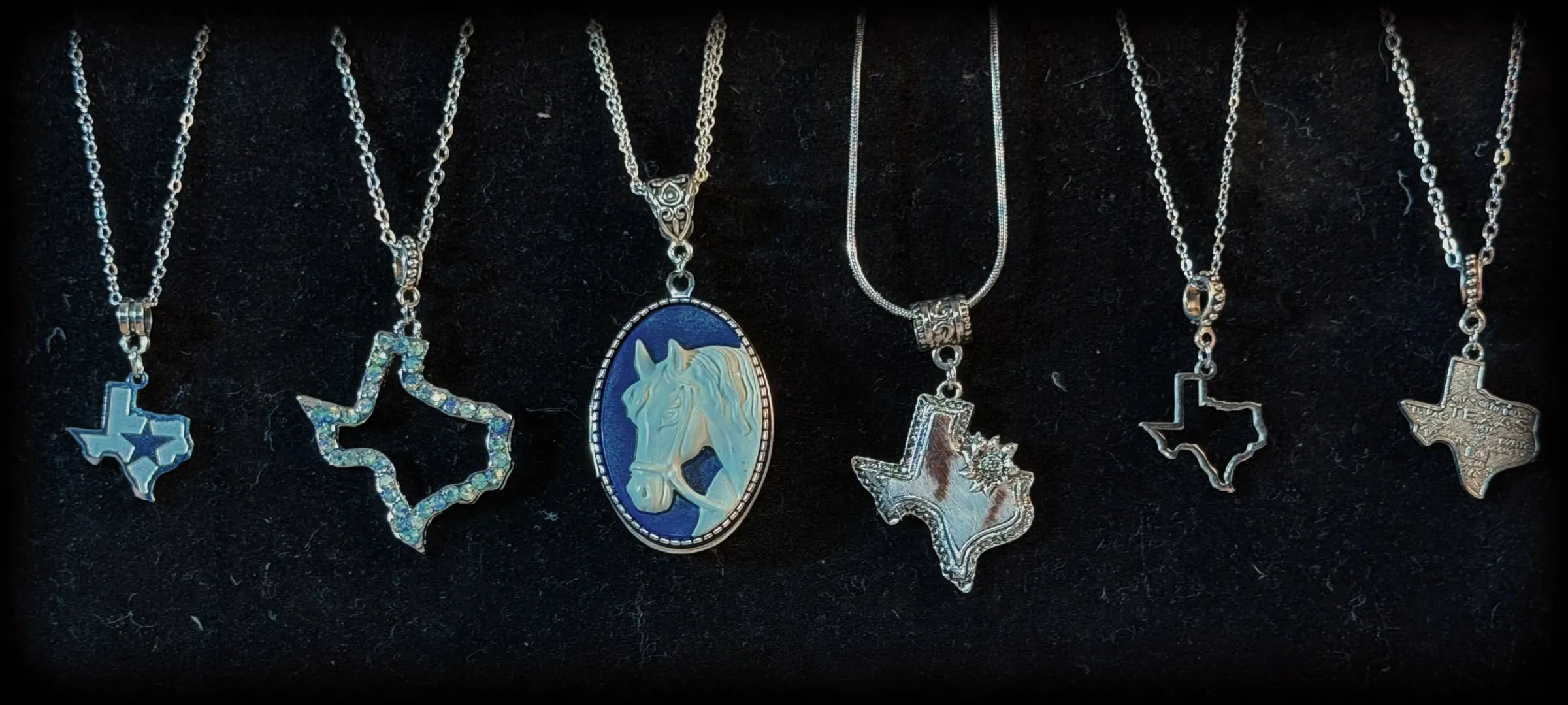Six pendants: five Texas-shaped charms and a navy horse cameo