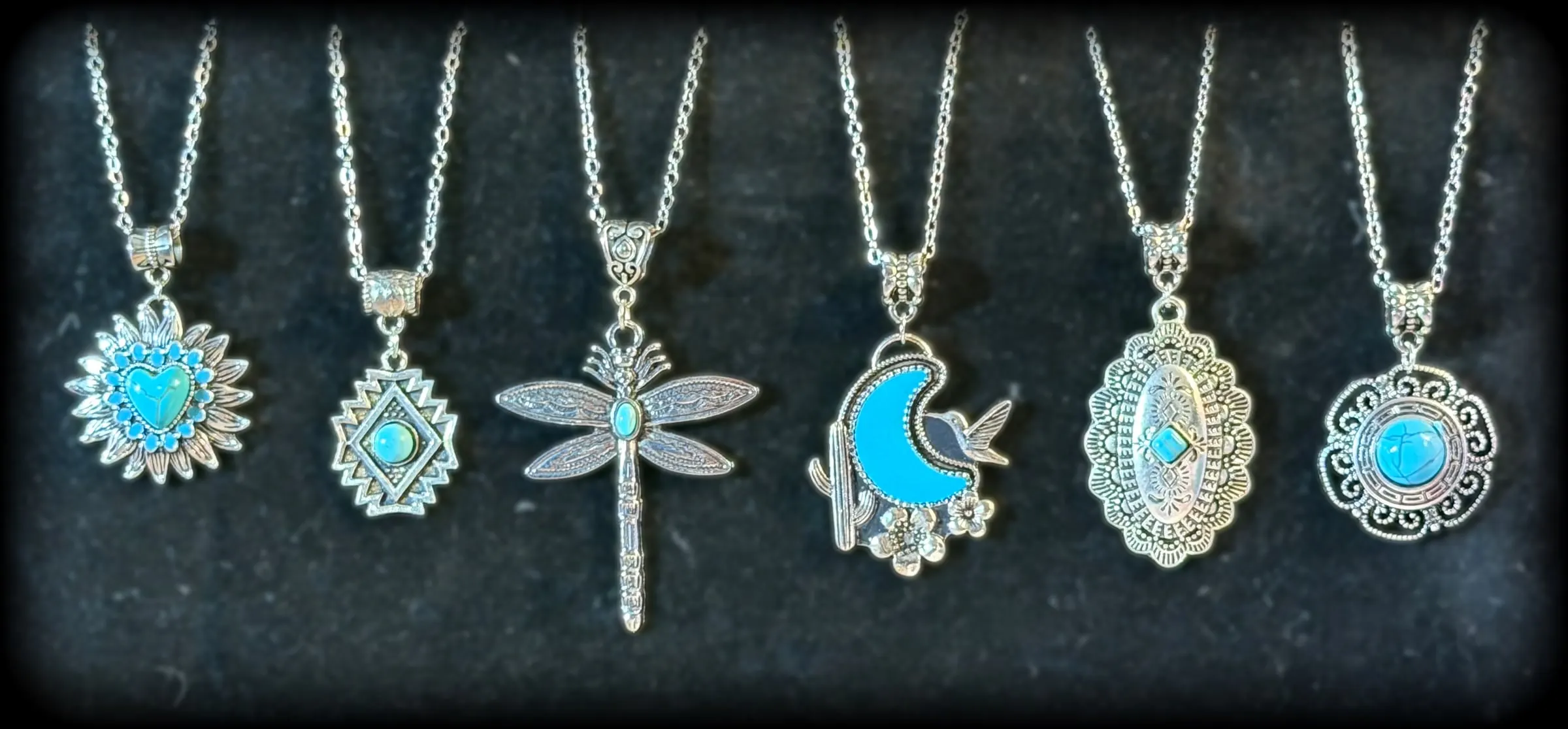 Six silver and turquoise pendants: a heart sunburst, an Aztec diamond, a dragonfly, a moon with a hummingbird, a tooled oval and a scrolled medallion