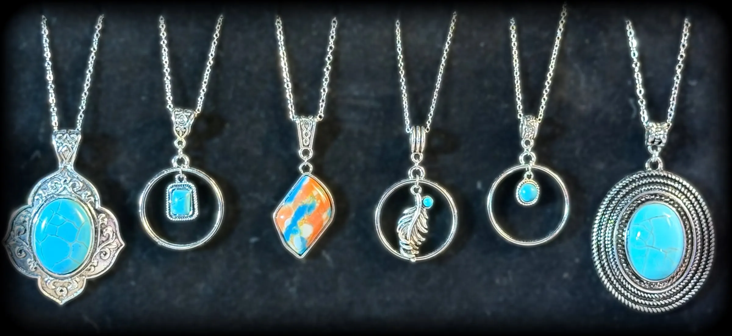 Six pendants: a scalloped turquoise oval, a turquoise square halo, an orange and turquoise stone, a feather halo, a turquoise dot halo and a rope-framed oval