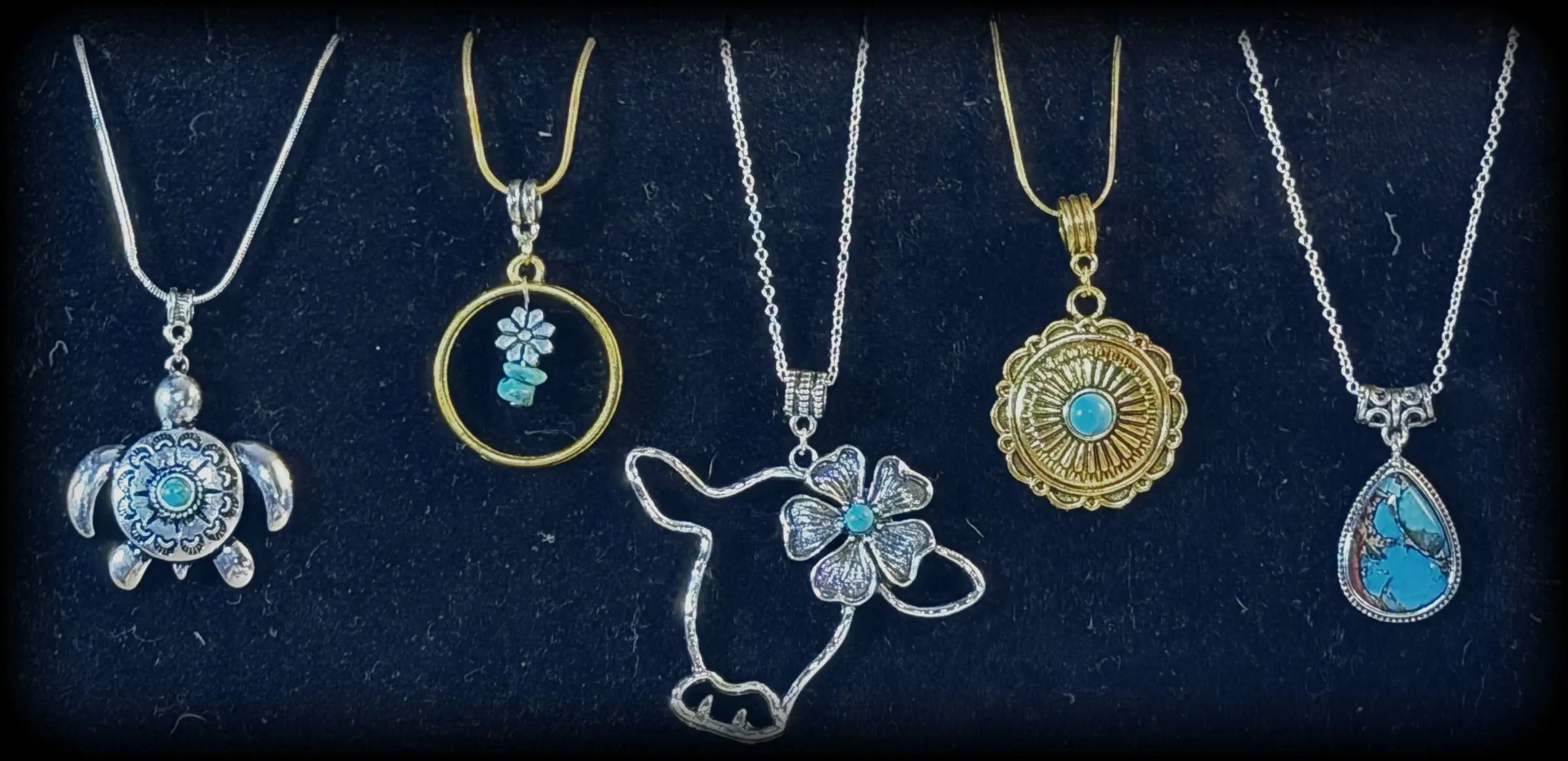 Five pendants: a turquoise sea turtle, a turquoise daisy halo, a cow with a flower, a gold sunburst concho and a turquoise matrix teardrop