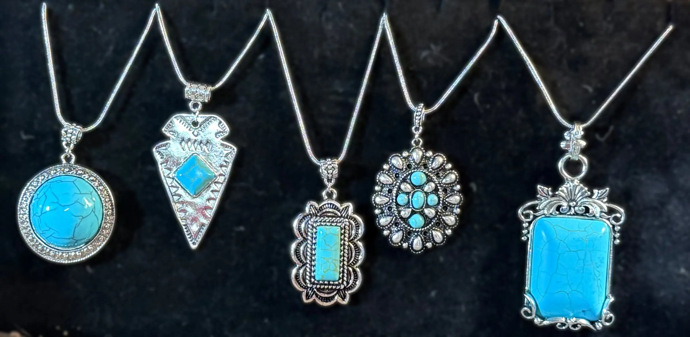Five bold turquoise pendants: a round stone, an arrowhead, a scalloped bar, a cluster oval and a cracked turquoise rectangle