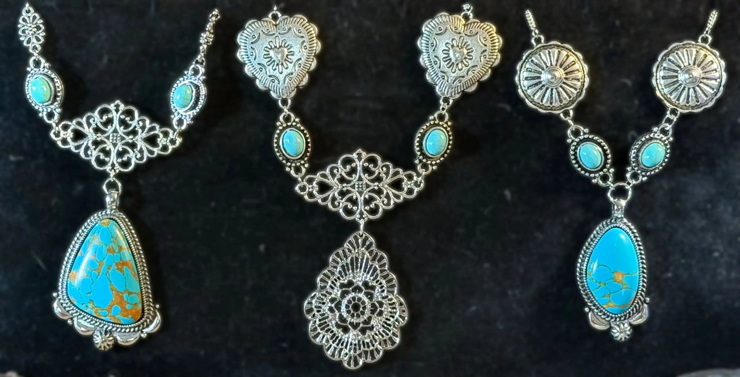 Three statement necklaces: a turquoise teardrop on filigree, a heart-concho lace drop and a sunburst concho with turquoise