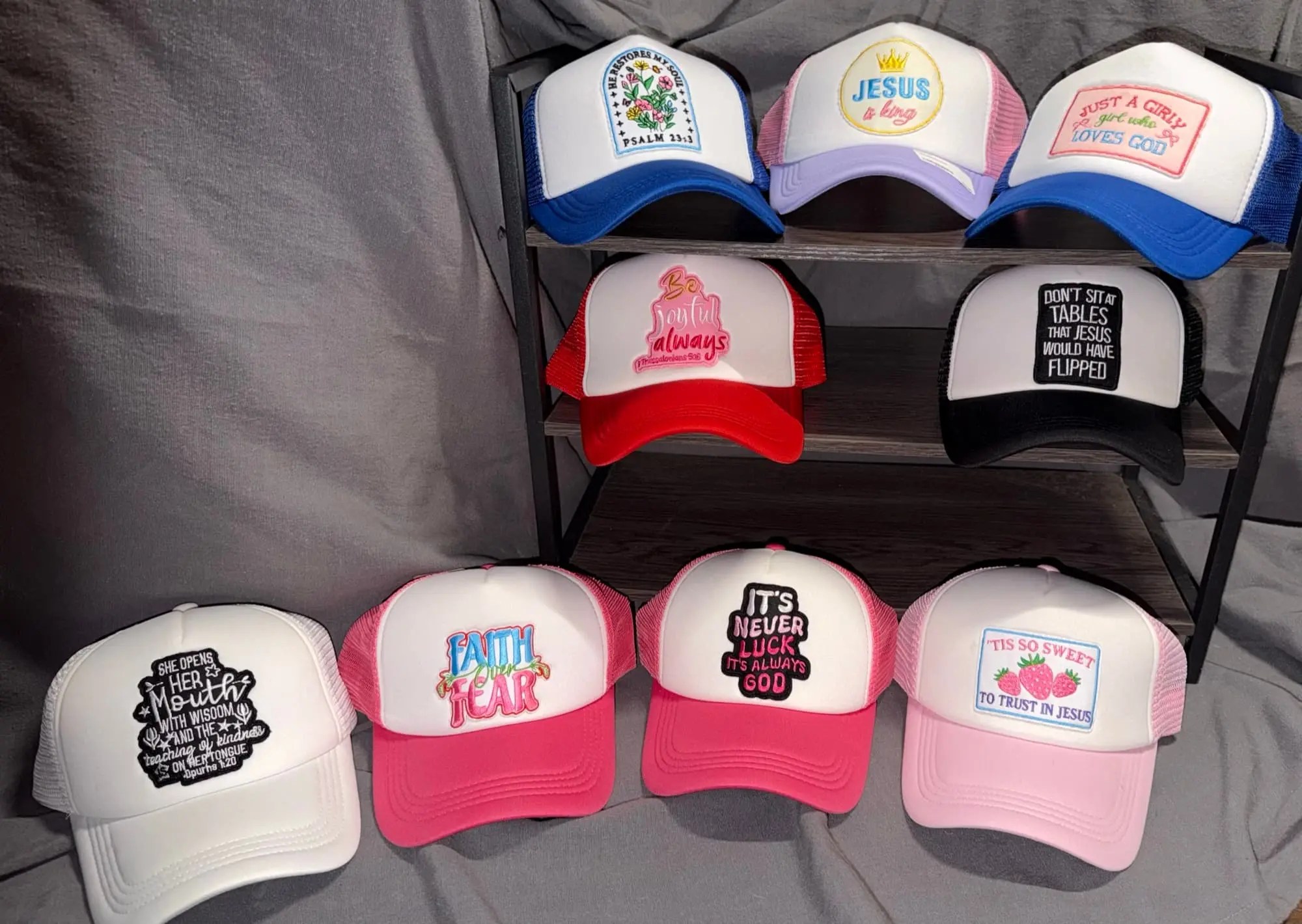 Nine faith-themed trucker hats: Psalm 23:3, Jesus Is King, Just a Girly Girl Who Loves God, Be Joyful Always, Don't Sit at Tables Jesus Would Have Flipped, She Opens Her Mouth With Wisdom, Faith Over Fear, It's Never Luck It's Always God, and 'Tis So Sweet to Trust in Jesus