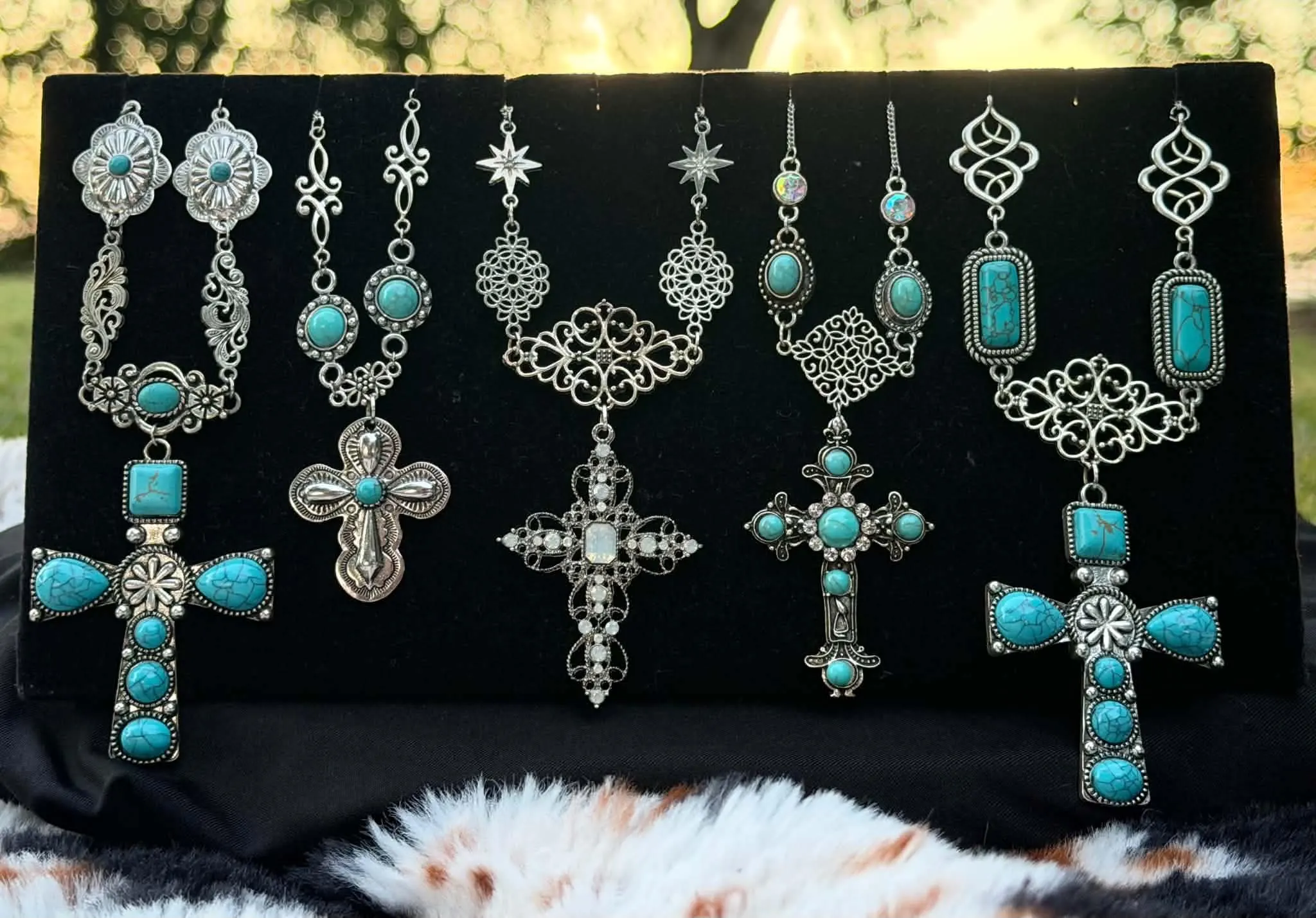 Five handmade turquoise and silver cross necklaces on a black velvet display
