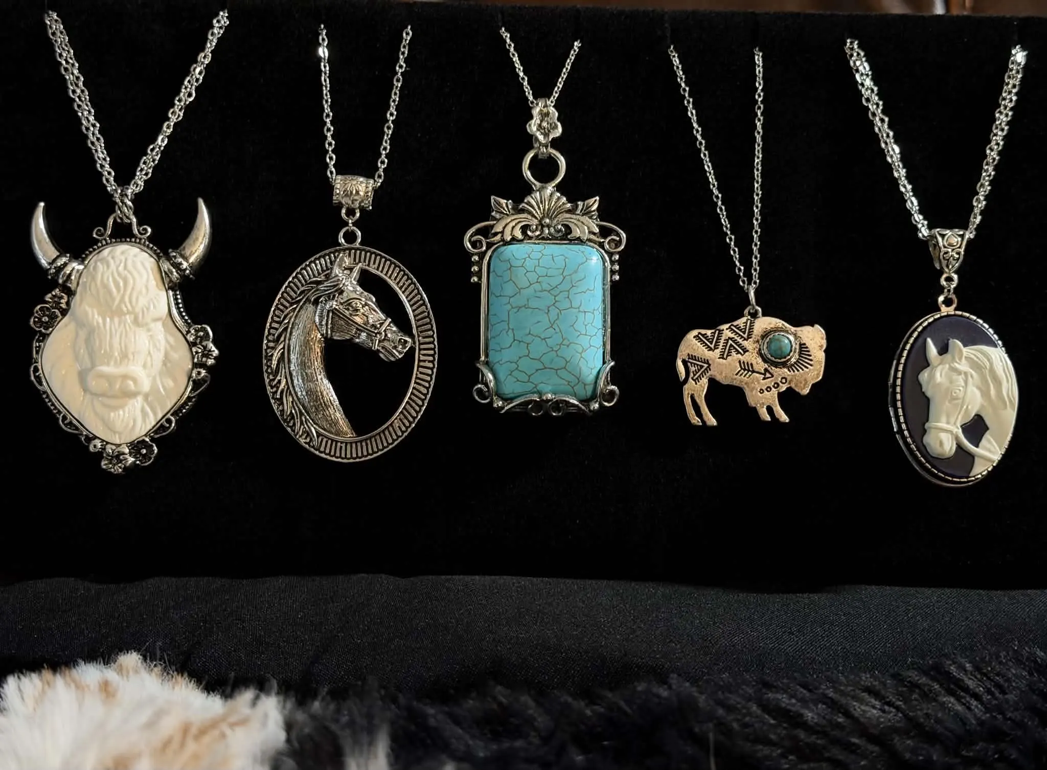 Five western pendant necklaces: a carved buffalo, a horse head, a turquoise slab, a copper bison and a horse cameo