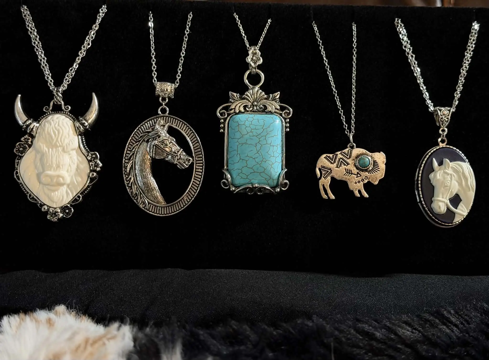 Five western pendant necklaces: a carved buffalo, a horse head, a turquoise slab, a copper bison and a horse cameo